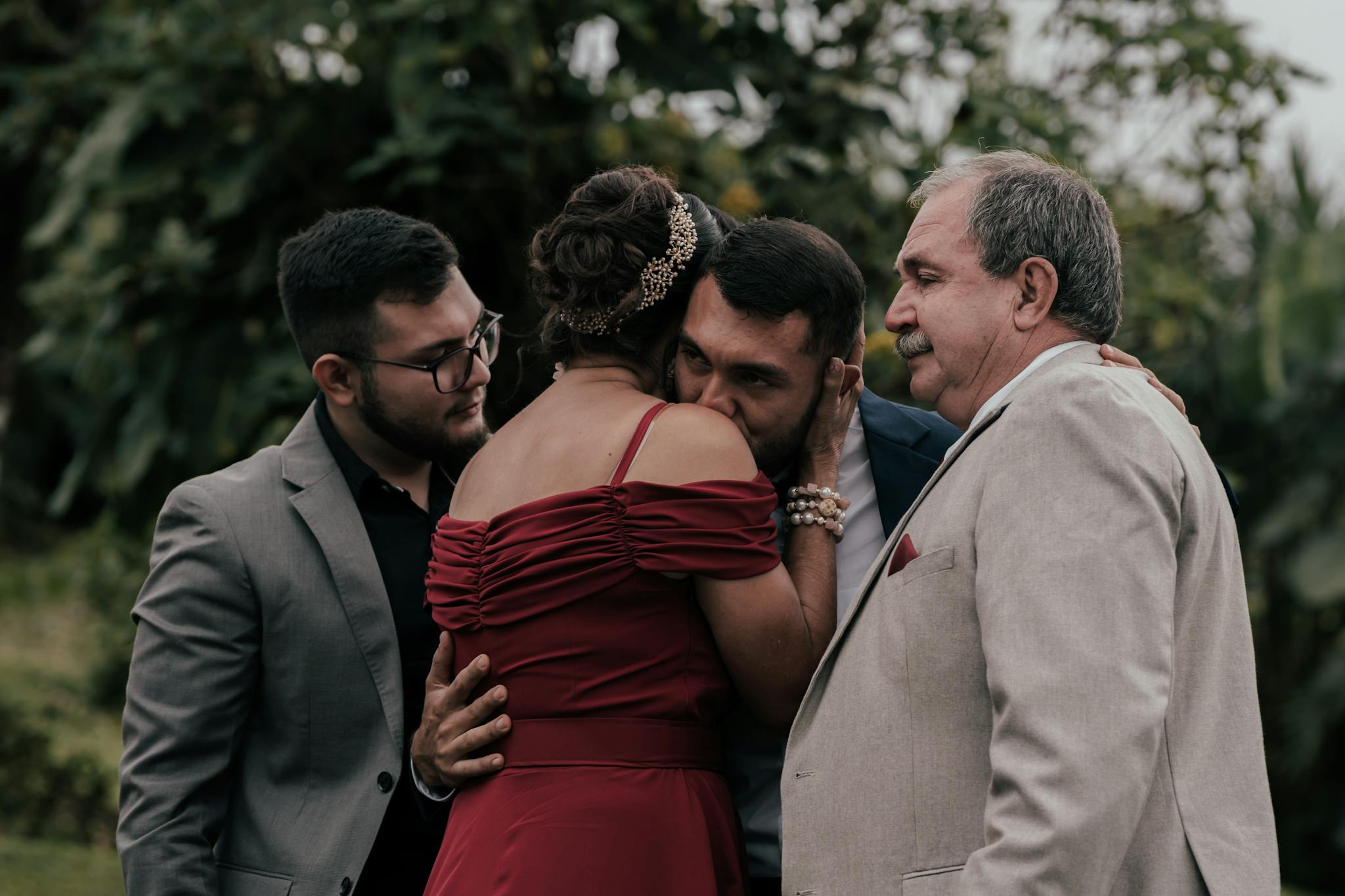 Family gathered outdoors in a close embrace, expressing deep emotions.